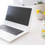 Acer chromebook on white desk with flower in vase beside it.jpg